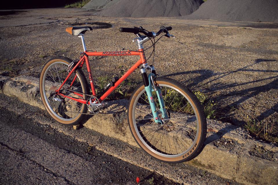 The same Ridgeback 601GS frame, still faded, but with lots of new components, a 1x10 drivetrain, and cyan Rock Shox forks.