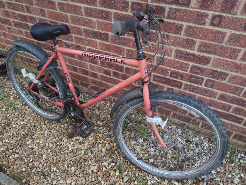 A sad-looking Ridgeback 601GS from the early 1990s, with a faded orange frame, components that don't fit quite right, broken cables and flat tyres.